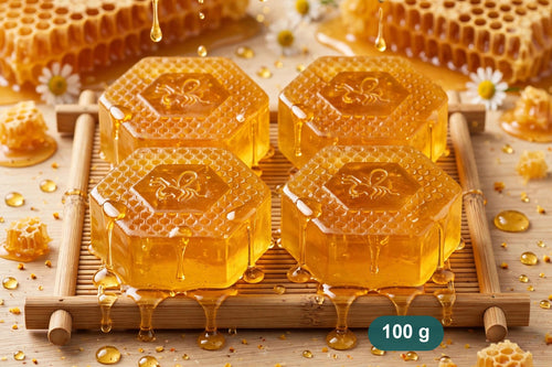 Four hexagonal honey soaps on a bamboo tray with honeycomb